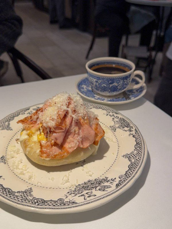 Пшеничная лепешка со скрэмблом и мортаделлой на расписной тарелке; видно текстуру лепешки и тонкие ломтики мортаделлы сверху.