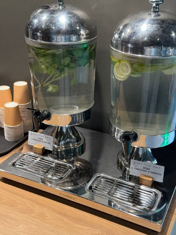 Станция с диспенсерами воды с лимоном и травами и одноразовыми стаканчиками — зона бесплатных напитков для гостей после процедур.