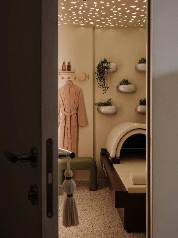 Дверной проём в приватную спа-комнату: видно халат, полки с косметикой и тёплое приглушённое освещение для релакса.
