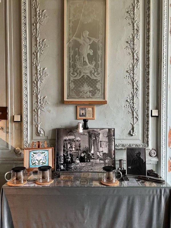 Лепнина и картины на стене, старинные фотографии и сервировка на консоли — детальный интерьерный фрагмент Дома Бака.