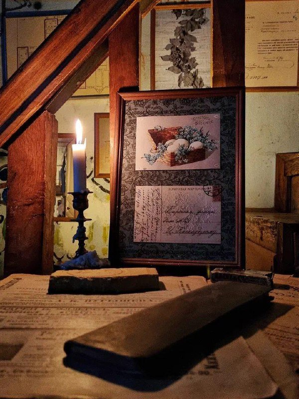 Крупный план рабочего стола с нотами, рамками и свечой: винтажные предметы и настольная композиция в помещении Дома Бака.