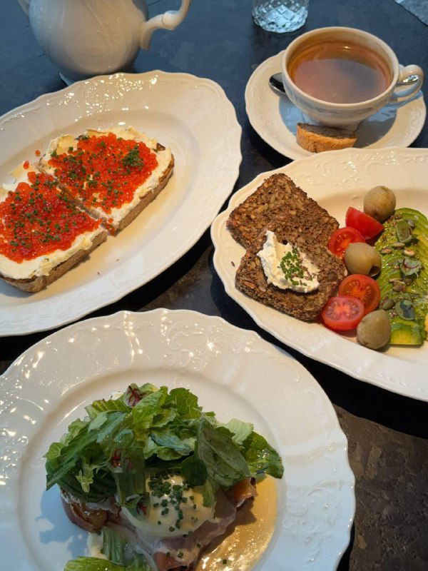 Несколько тарелок на столе: бутерброд с красной икрой, ржаной хлеб с намазкой и бенедикт — композиция блюд и напитков для позднего завтрака в Tetto.