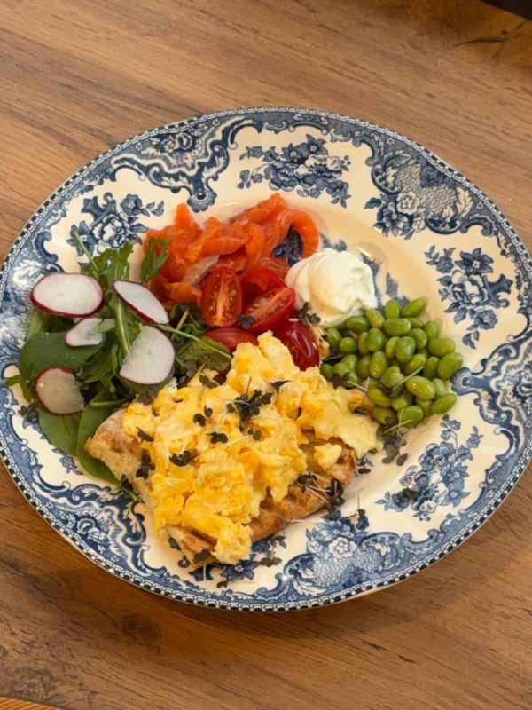 Тарелка с яичницей-скрэмблом, эдамаме, салатом и маринованными овощами на винтажной синей тарелке — яркая композиция завтрака в 8:am.