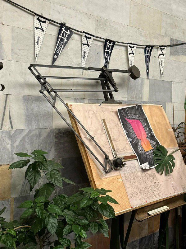 Декоративный мольберт и винтажный светильник у стены — элементы оформлении, напоминающие оборудование советского института в кафе.