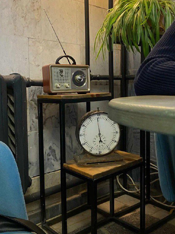 Старинное радио и настенные часы на металлической подставке — ещё одна винтажная деталь, вписанная в интерьер кофейни.