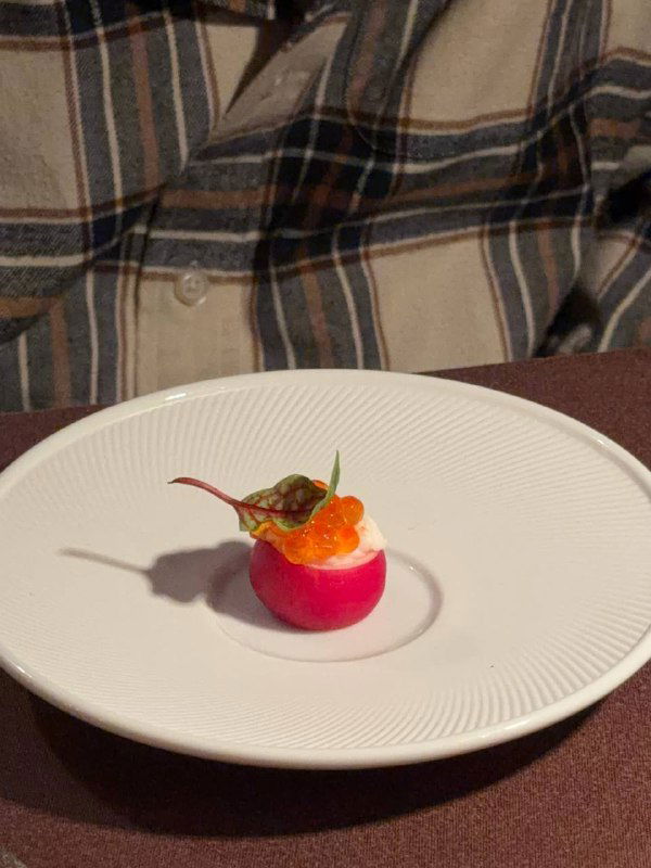 Миниатюрная авторская закуска на белой тарелке — яркий розовый шар с икрой и зеленью, элегантная подача в сете 83 в ЕМ