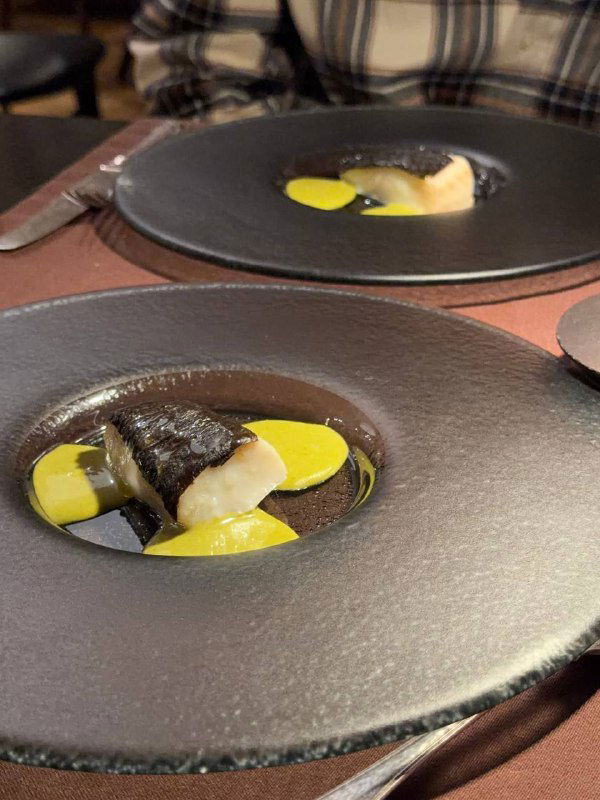 Две чёрные глубокие тарелки с деликатными белыми элементами и жёлтым соусом — визуально контрастная подача в сете ресторана ЕМ