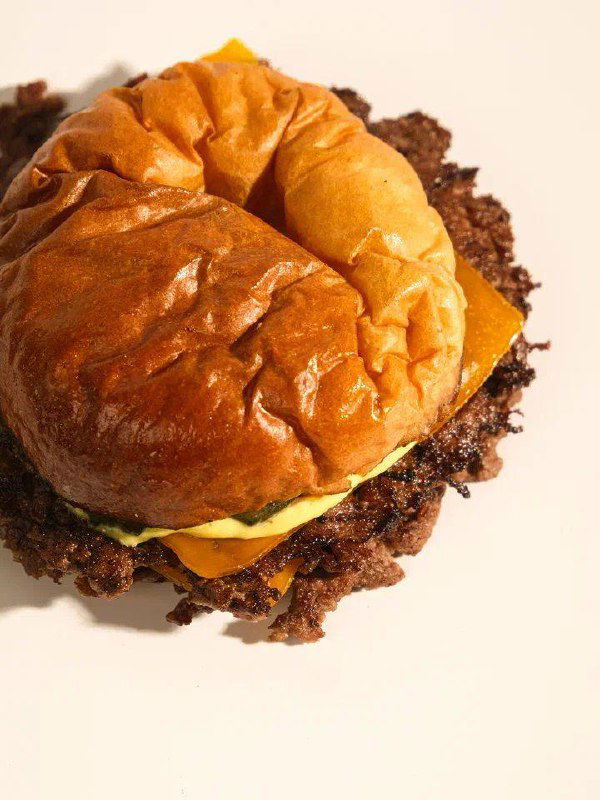 Смэш-бургер BUMO крупным планом: тонкая прижатая котлета с хрустящими краями, плавленый сыр и слегка помятый мягкий верх булочки.