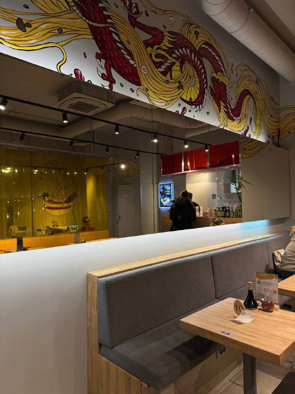 Вид на стену ресторана с японским орнаментом и частично видимая стойка выдачи блюд — интерьер с арт-акцентом в Asiatiq.