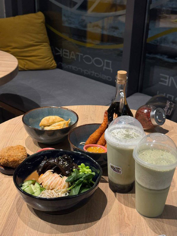 Стол с подачей: миски рамэна, закуски и два напитка в пластиковых стаканах — общий кадр заказа до подачи десерта.