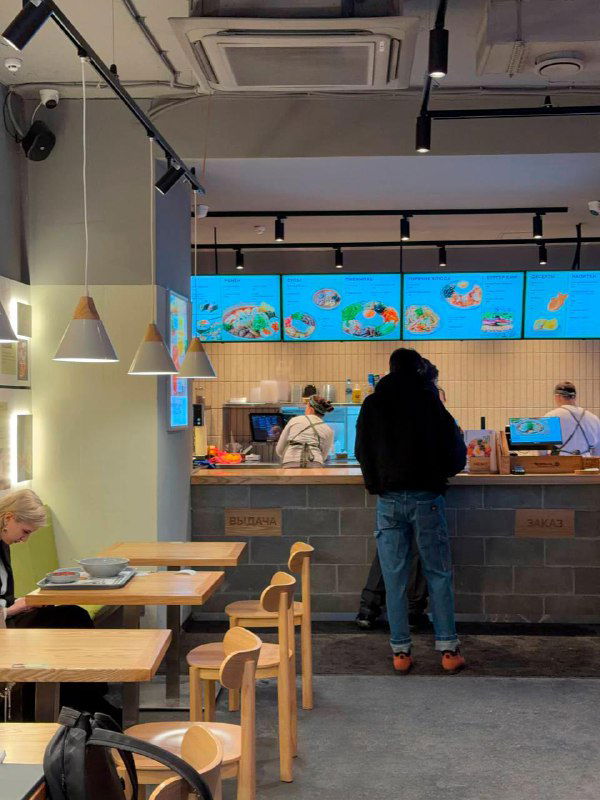 Касса и зона выдачи в Koreana Light: стойка, персонал и светящиеся меню на стене — видно формат самообслуживания и быстрый ритм заведения.