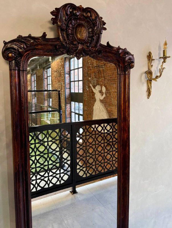 Декоративное зеркало и балконный пролёт с видом на корт в клубе «Ракета»: декоративные элементы, решётка и часть площадки видны в отражении.