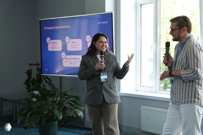 Спикеры ведут обсуждение перед экраном с инфографикой; в кадре живая коммуникация и обмен идеями в формате доклада.