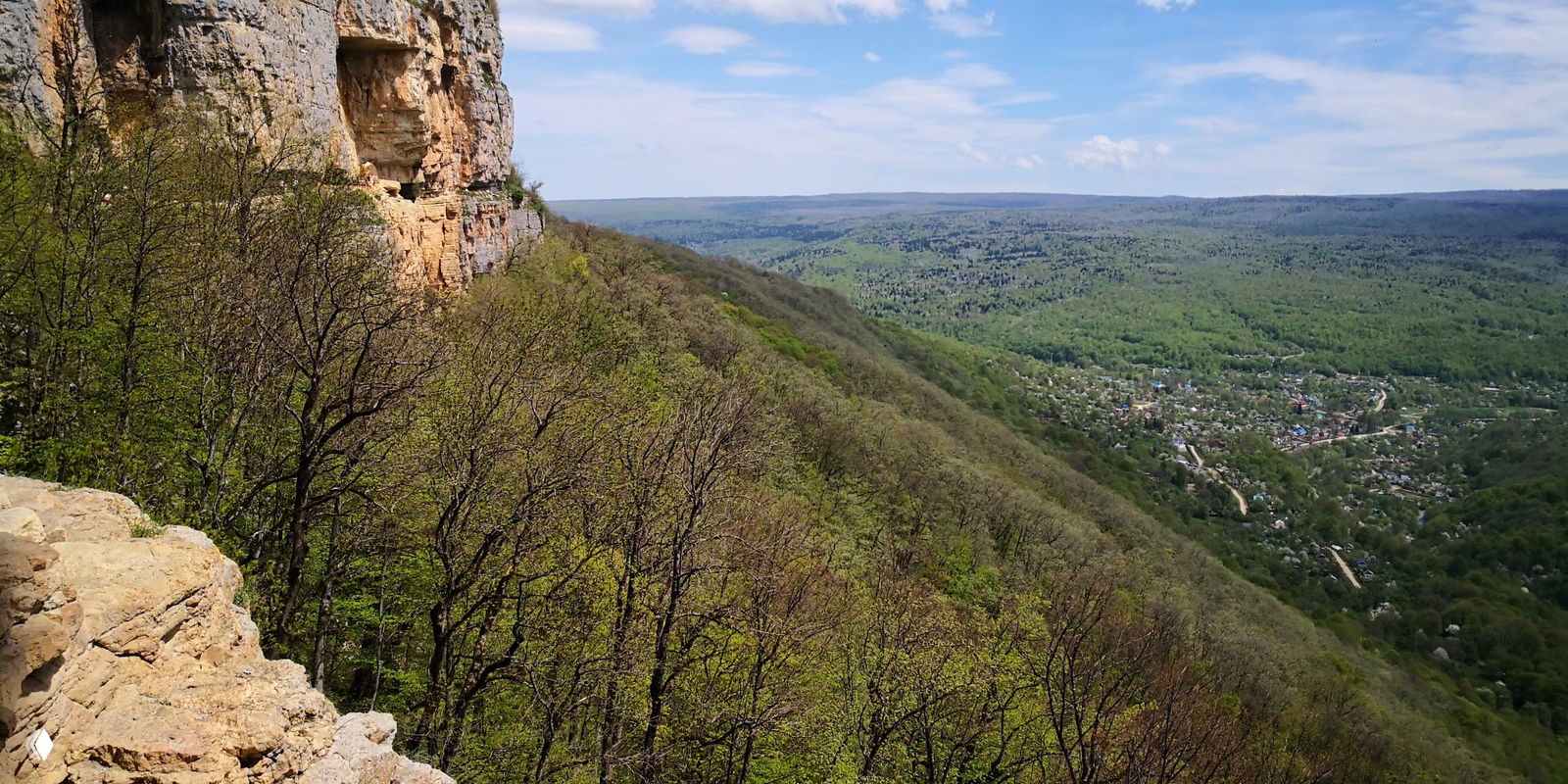 Широкий вид с выступа скалы на горизонтальную линию хребтов и открывающуюся перед ними панораму нагорья Лагонаки и зелёной долины.