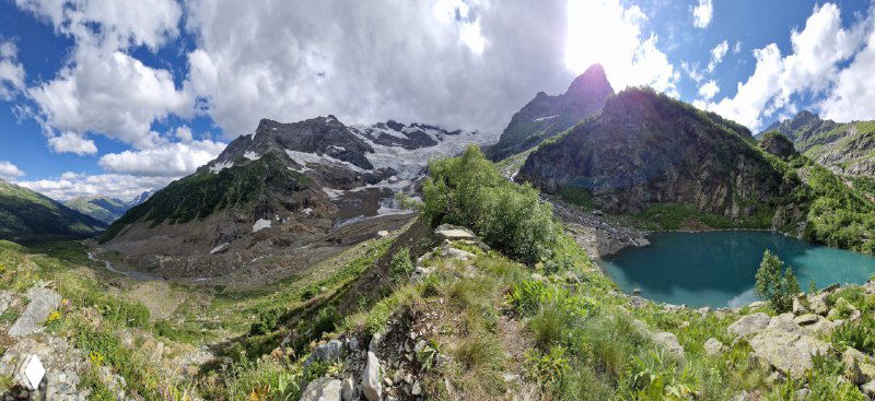 Панорамный вид на Турье озеро с ледником и горными пиками позади: сочетание бирюзы воды, белого льда и скалистых отрогов