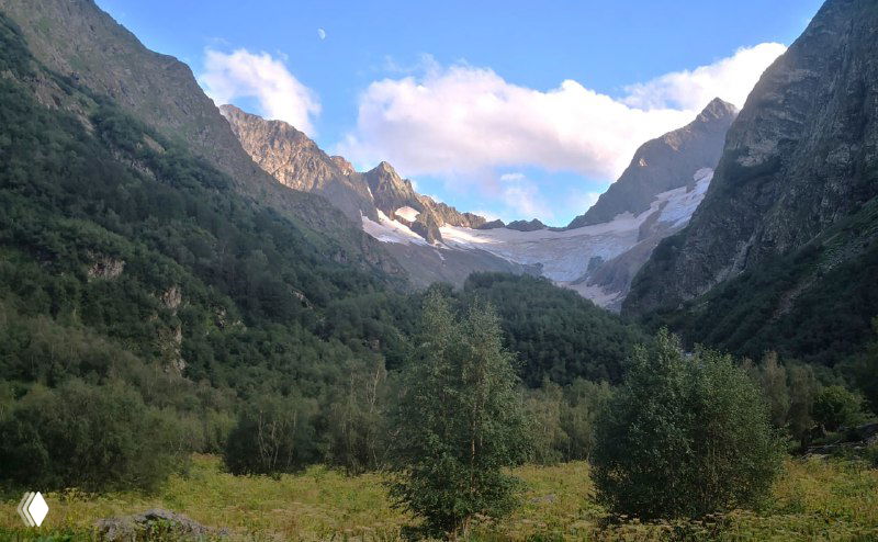 Ущелье Домбай‑Ульген в мягком вечернем свете: открытая лощина, куполообразные вершины и спокойная атмосфера после дождя.
