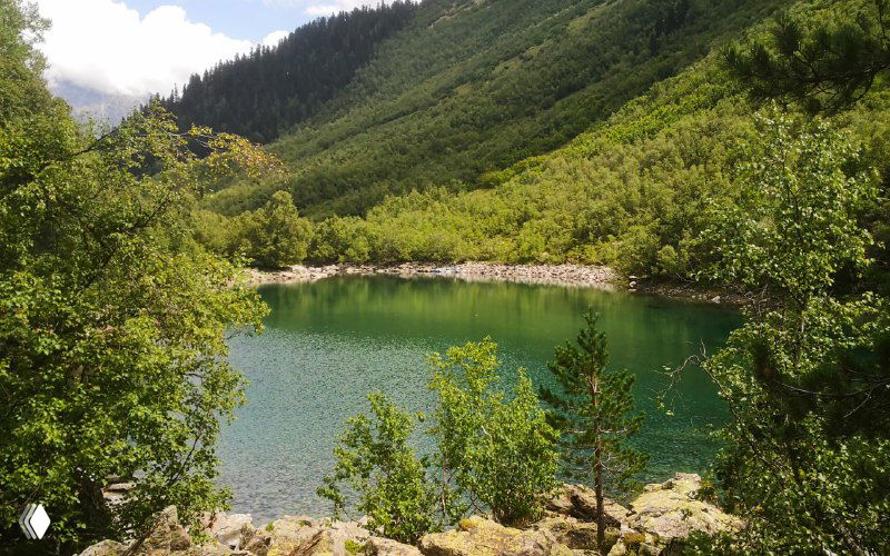 Небольшое круглое озеро в горной котловине, окружённое зеленью и каменистыми берегами, типичный вид одной из чаш Бадукских озёр.