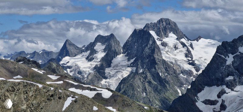 Крупные скальные пики и снежные карнизы Мусса-Ачитары крупным планом, рельефы и трещины в снегу отчетливо видны.