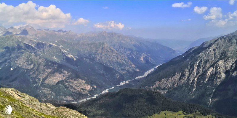 Дальний вид вниз по долине с извивающейся рекой и лесистыми склонами — панорама окружения Домбая с высоты.