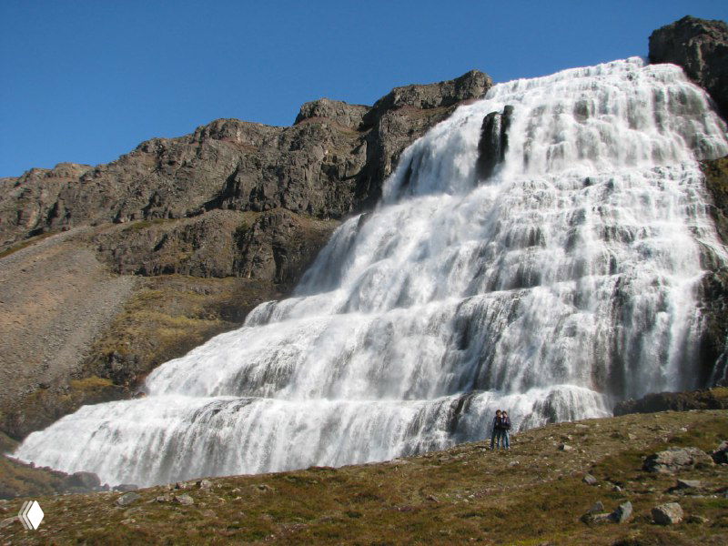Крупный план белого конуса водопада Диньянди — мощный поток воды, падающий по ступенчатой поверхности скалы.