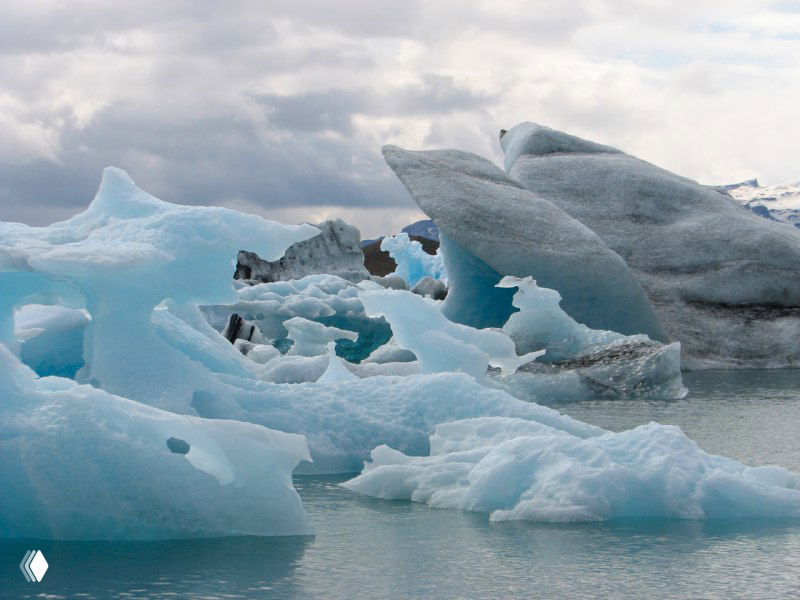 Крупный план переплетённых кусочков льда в лагуне Йокулсарлон, текстуры голубого и белого льда под пасмурным небом.