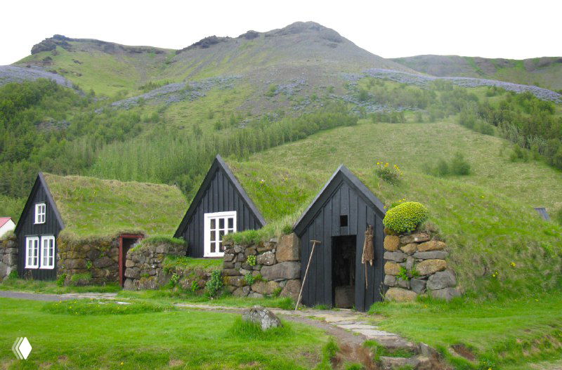 Традиционные исландские домики с торфяными крышами в музее народного быта, окружённые зелёными холмами и ухоженным газоном.