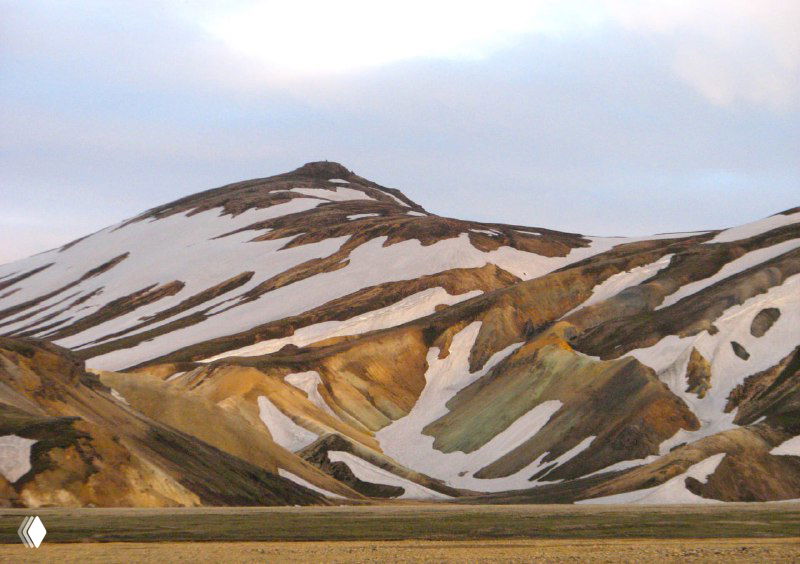 Крупный план риолитовых склонов с пятнами снега и цветными породами, типичный ландшафт Ландманналойгара.