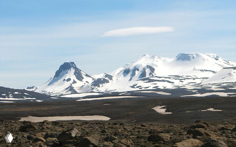 Вид на вулканические конусы и каменистое плато Кьолур: рассеянные валуны, остатки снега и широкий небесный свод в походном маршруте через нагорье.