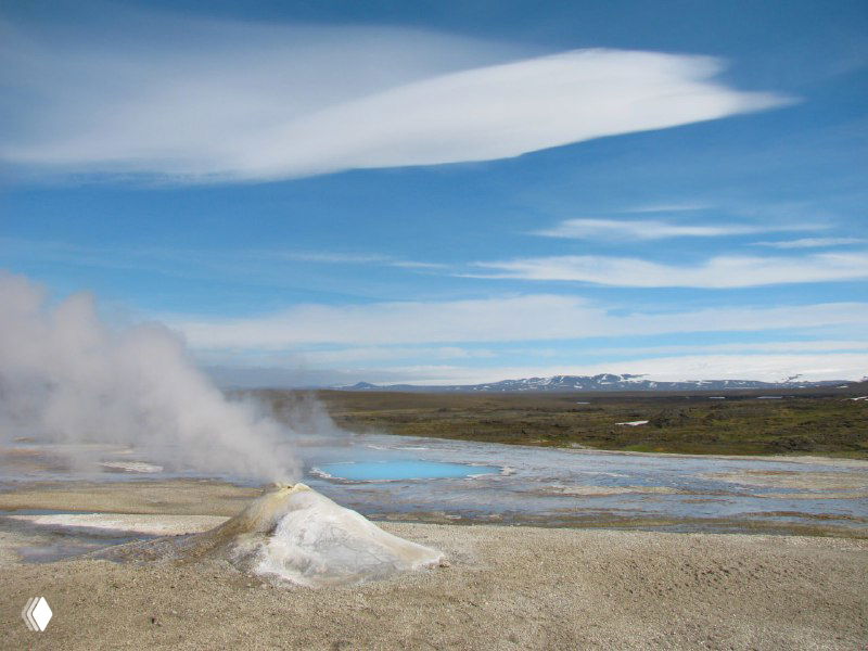Термальная зона Квераведлир с парящими источниками, разноцветными минеральными отложениями и белыми клубами пара над влажной почвой на равнине.