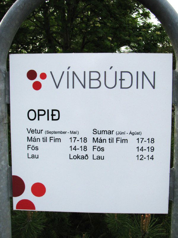 Табличка винной лавки VÍNBÚÐIN с указанием часов работы в Исландии: логотип, расписание открытия по дням и характерный строгий дизайн вывески.