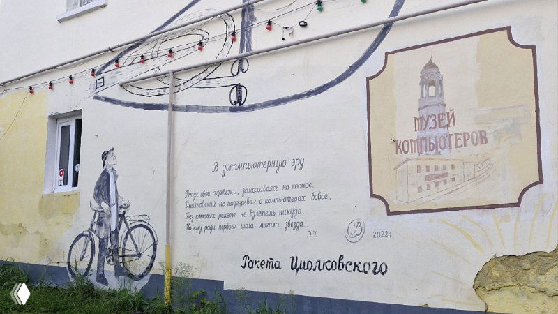 Фрагмент настенной росписи и вывеска «Музей компьютеров» на фасаде, изображение старинного велосипеда и текст на стене.