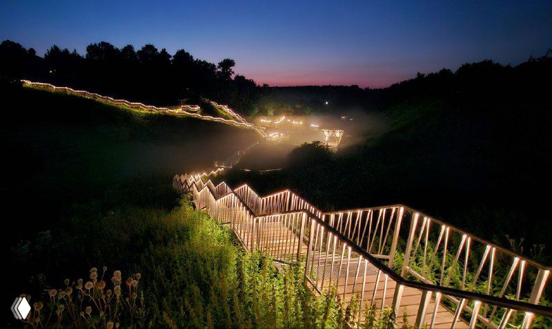 Ночной вид парка Текижа: освещённые ступени и огоньки вдоль оврага, превращённого в арт-пространство, мерцающая тропа вниз.