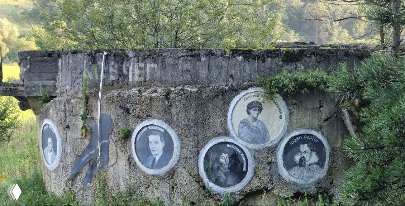 Круглые портреты в медальонах на бетонной стене у старого сооружения — ряд фотографоподобных изображений людей, мемориальный мотив