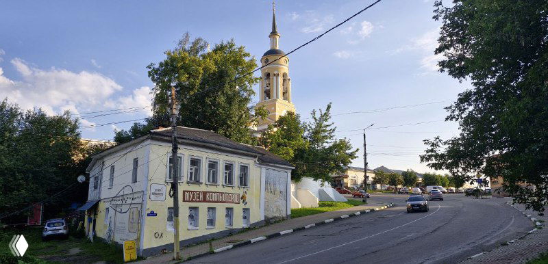 Улица в Боровске с колокольней на горизонте: невысокие дома, тротуар и ясное небо над исторической застройкой города.