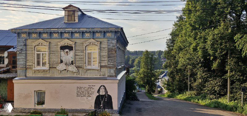 Деревянный дом в Боровске с настенной росписью и резными наличниками: традиционная архитектура и уличный арт на фасаде.