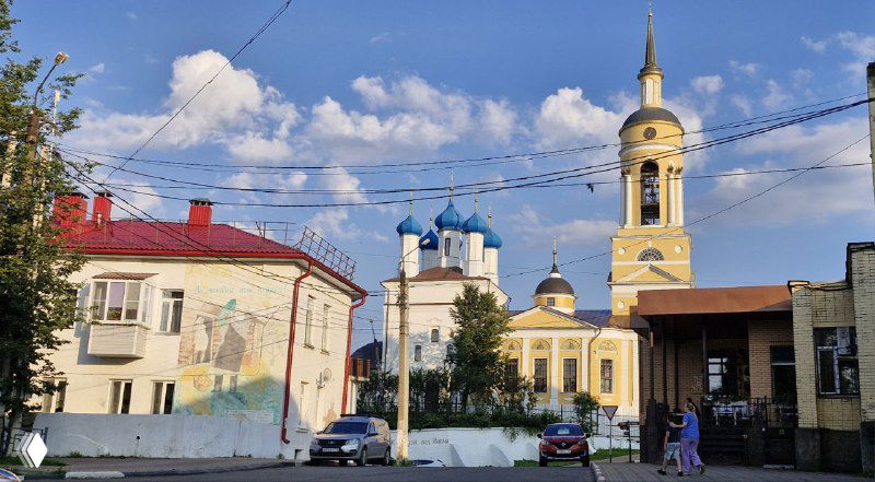 Вид на несколько храмовых куполов и колокольню через городскую улицу: сочетание старинной архитектуры и городской среды.