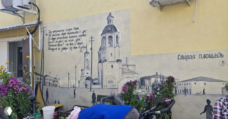 Фреска на фасаде дома в Боровске: настенная живопись с историческими сценами и цветами в кадре у стены.