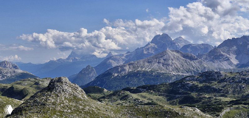 Горные пики Доломитов и широкий горный ландшафт — скалы, гребни и далекие вершины под ясным небом.
