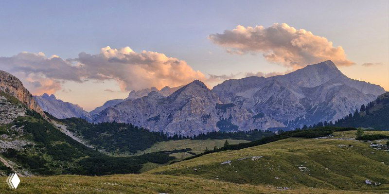 Альпийский закат над хребтом Доломитов: розово-оранжевые облака и силуэты гор над пастбищем у рефуджу.