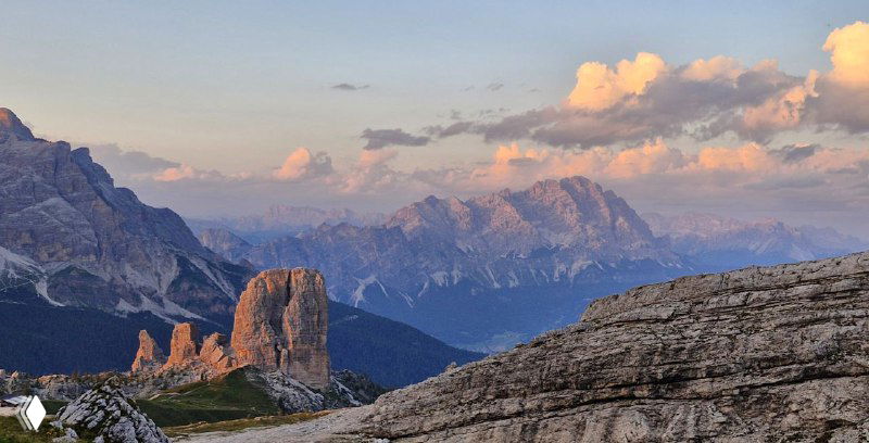 Пять Башен в вечернем свете: закатное освещение на фоне дальних пиков Доломитов, тёплые тона и длинные тени в высокогорье.