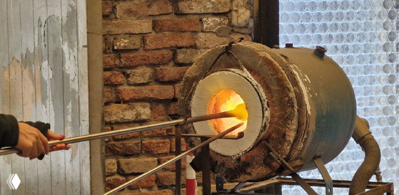 Печь и мастерская для выдувания стекла: раскалённый очаг, металлическая трубка и кирпичная стена мастерской, вид процесса изнутри.