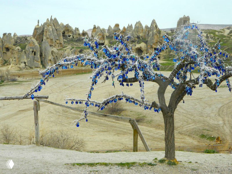 Дерево с висящими амулетами на фоне грязевых долин и перибаджаларых конусов — характерный пейзаж окрестностей Гёреме в Каппадокии.