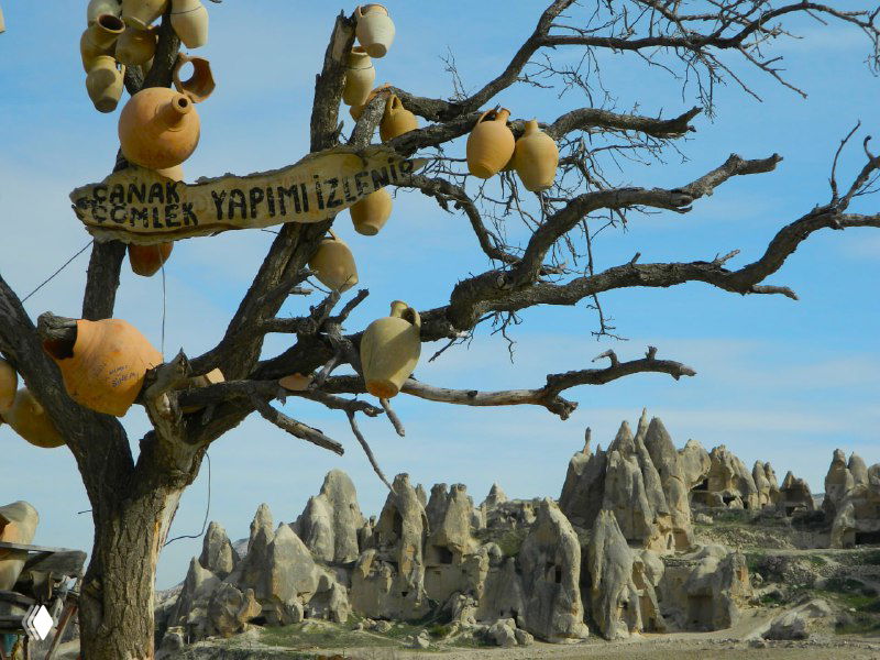 Декоративные керамические сосуды на сухом дереве на переднем плане, за ними видны конусы перибаджалары и скалистые образования Гёреме.