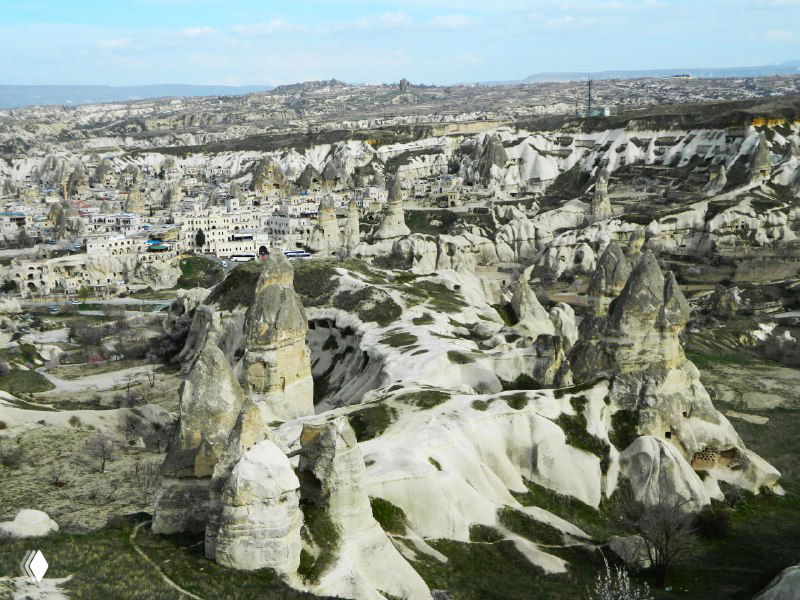 Широкий панорамный ракурс на долину перибаджалары с многочисленными зубчатыми столбами и мягкими туфовыми образованиями под голубым небом.
