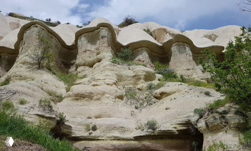 Крупный план волнообразных туфовых слоёв с гладкими уступами и естественными неровностями на склоне одной из долин.