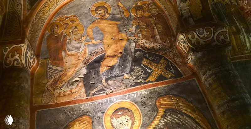 Интерьер пещерной церкви с хорошо сохранившейся раннехристианской фреской на своде; видны лица, нимбы и узоры.