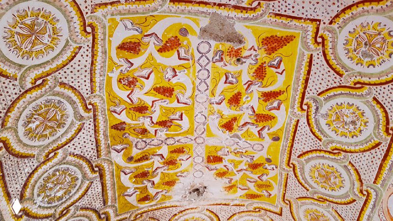 Детализация сложной росписи на потолке церкви — орнаменты и фигуры в тёплых тонах, сохранившиеся фрески внутри пещеры.