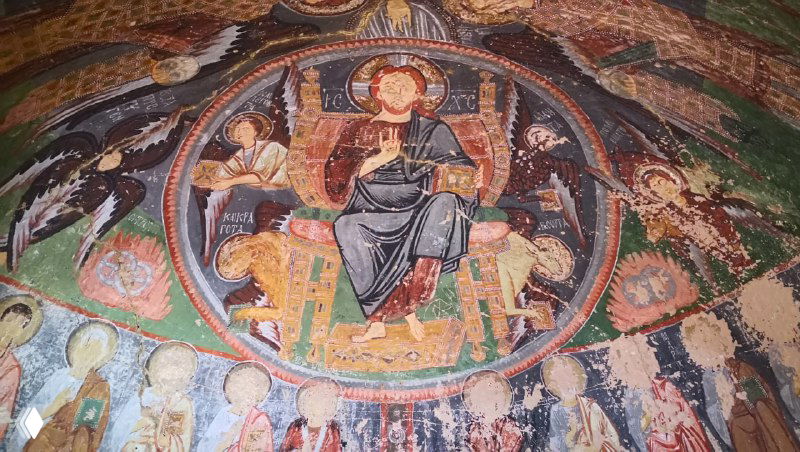 Куполообразная фреска с изображением Христа в мандорле и рядом фигуры святых на внутренней стене пещерной церкви, яркие цвета сохранились.