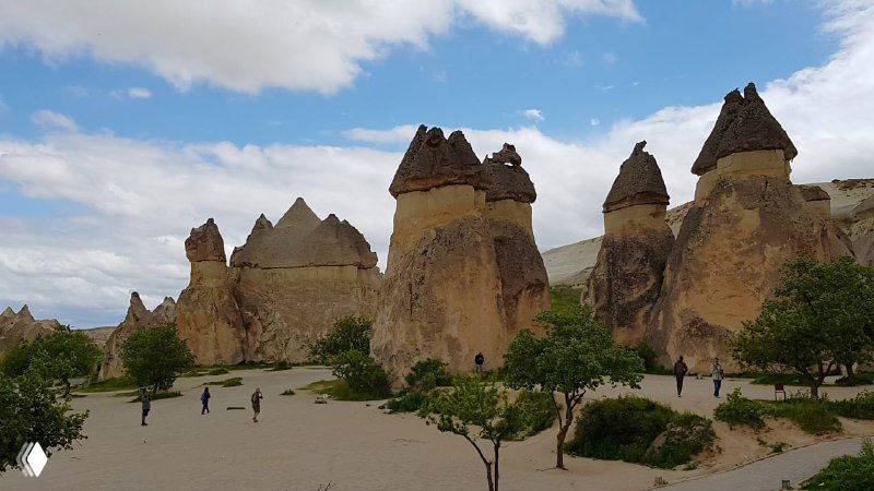 Широкий вид на центральную часть Пашабага: несколько массивных «грибов», посетители внизу и ровное грунтовое поле вокруг.