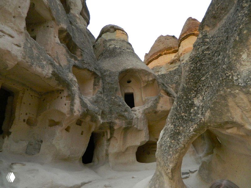 Входы в выдолбленные пещерные ниши внутри скального образования с округлыми проемами и следами древнего обитания.